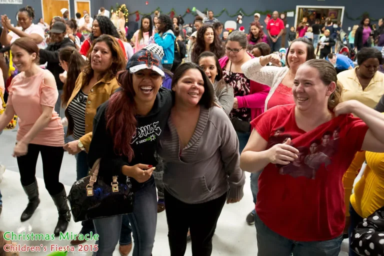 Moms and volunteers dancing together at the Christmas Miracle Fiesta