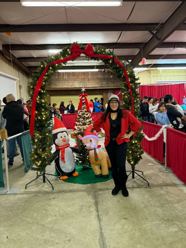 A volunteer beside the lighted Christmas arch at the entrance to the Fiesta